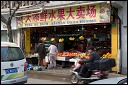 Woman in pajamas at Shanghai fruit and vegetable shop.