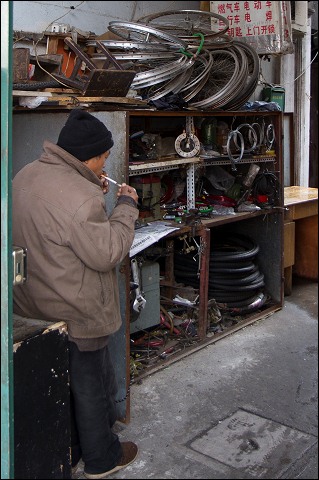 Bicycle mechanic in Shanghai alley.