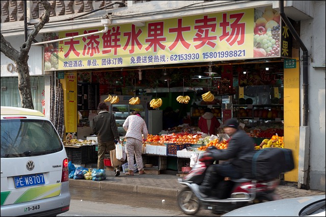 Woman in pajamas at Shanghai fruit and vegetable shop.