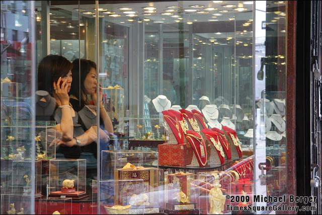 Woman on telephone, jewelry shop window on Canal Street. Chinatown, NYC.