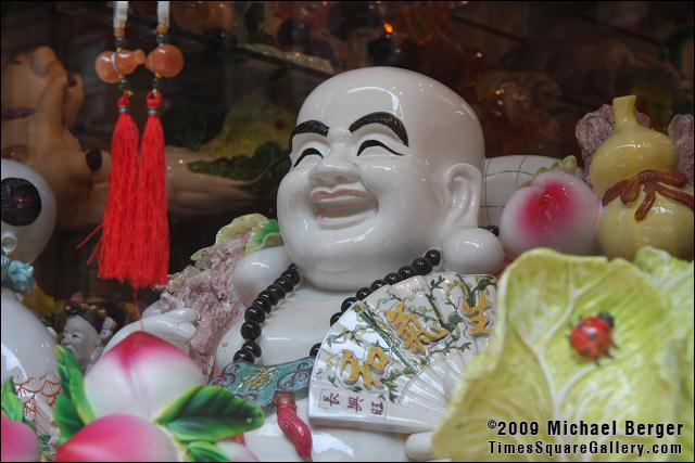 Smiling white and black porcelain buddha in shop window on Mott Street. Chinatown, NYC.