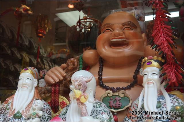 Smiling porcelain buddha and wise men in shop window. Chinatown, NYC.