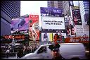 A John Lennon billboard, police officer, and gathering of Broadway performers in Times Square. 2001.