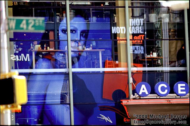 An ad reflected in the windows of a restaurant on W. 42nd Street between Broadway and 7th Avenue, 2000.